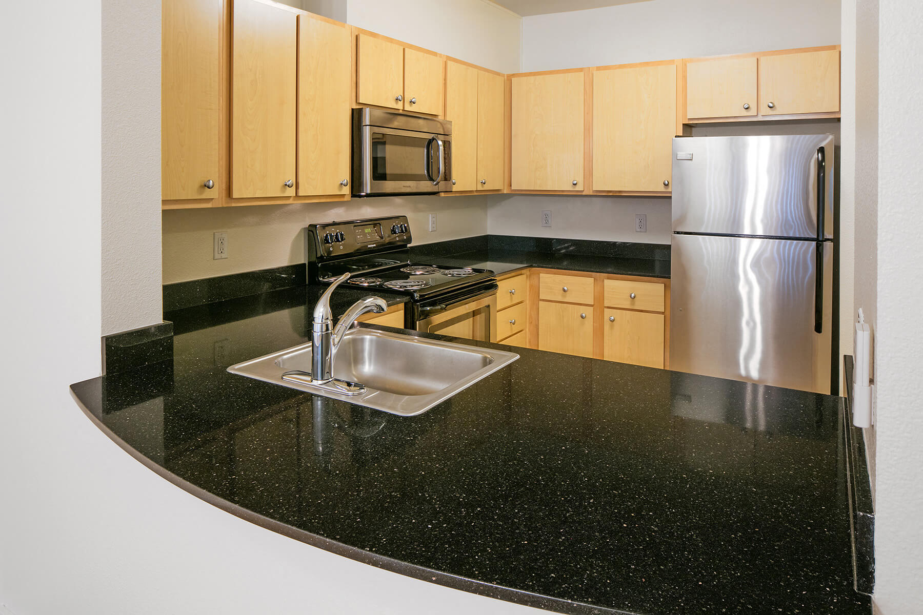 A kitchen with dark counters and at the Collins Circle apartments in Portland, Oregon.